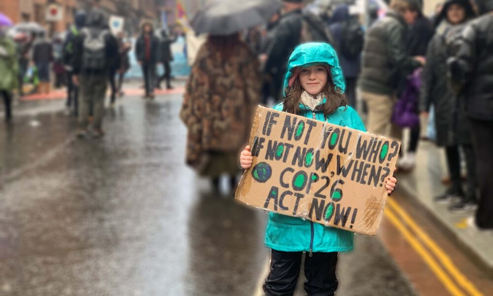 Girl holding cardboard sign that says 